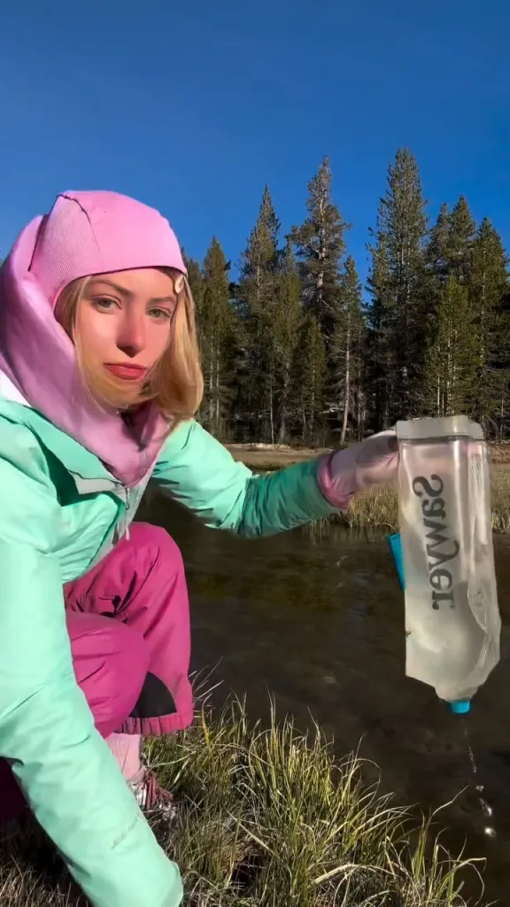 Kamryn Renae filling a water bottle from a stream.