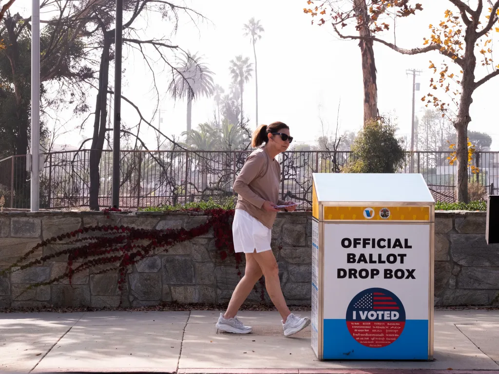 A person dropping a ballot into an Official Ballot Drop Box outside the Pacific Palisades Library, which was destroyed in fires earlier in the year.