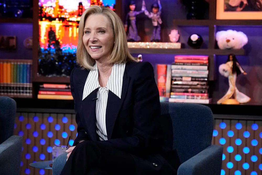 Lisa Kudrow smiling while seated on a television set.