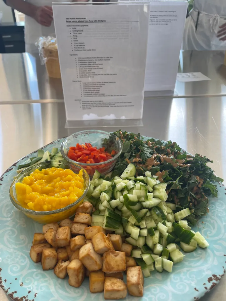 Tofu peanut nourish bowl with sides of mango, bell pepper, avocado, and kale.
