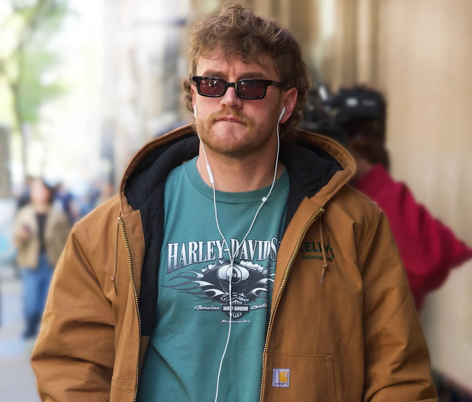 West Wilson wearing sunglasses and a brown jacket over a teal Harley-Davidson shirt.