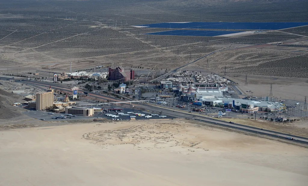 Aerial view of Primm, Nevada, showing Whiskey Pete's Hotel & Casino, Buffalo Bill's Resort & Casino, and Primm Valley Resort & Casino, with Interstate 15 and solar panels in the background.