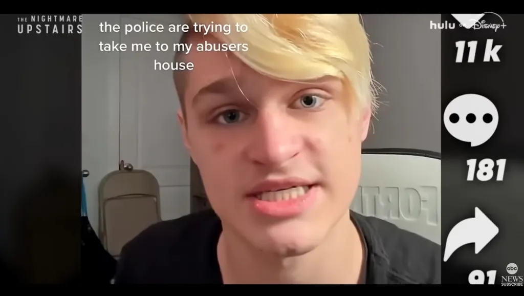 A person with blonde hair and blue eyes speaking into the camera with text overlay 