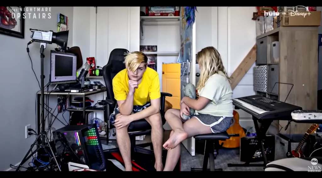 Brynlee and Ty Larson sitting in a room with a computer setup and a keyboard.