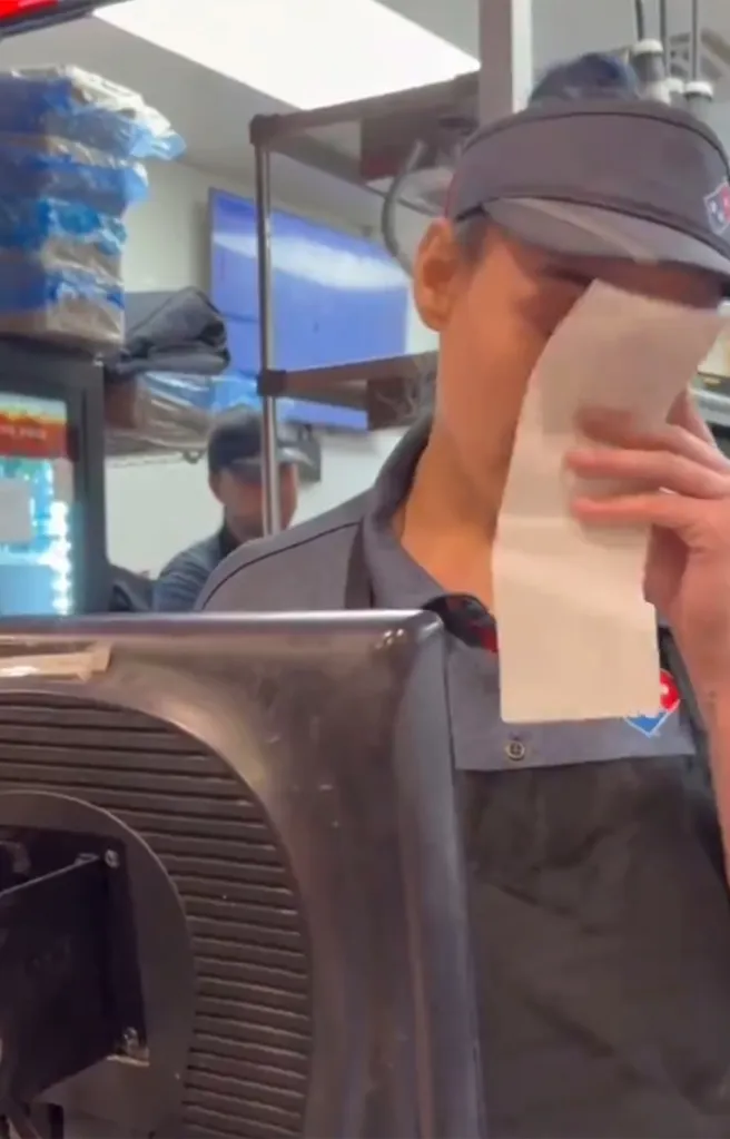 Woman employee at Domino's keeps her composure while wiping away tears.