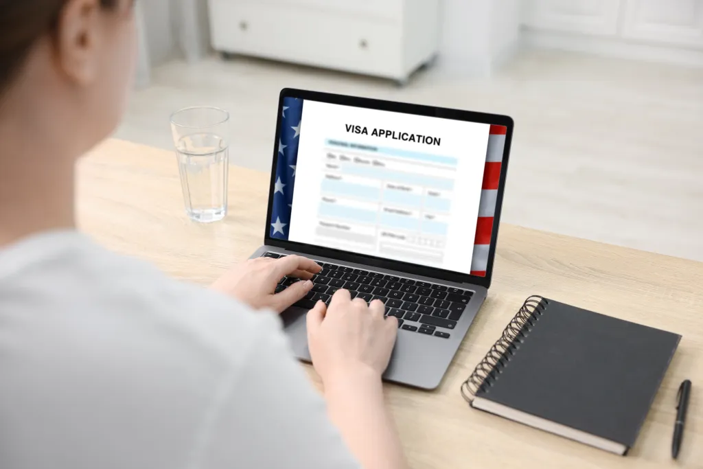 Woman filling out an online visa application form on a laptop.