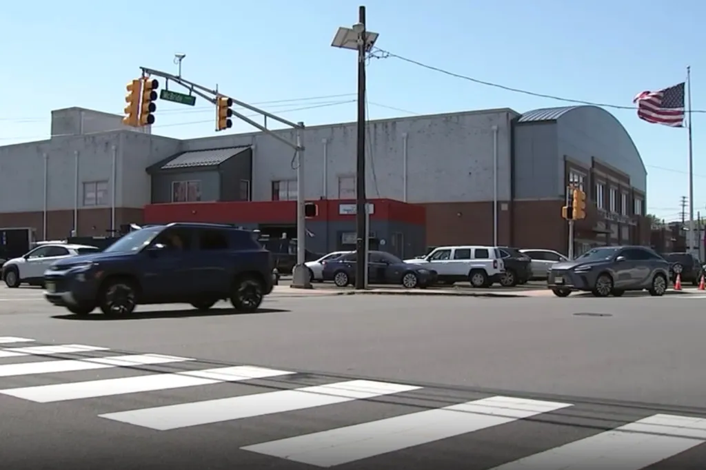 A street intersection with a crosswalk, traffic lights, and several cars on the road.