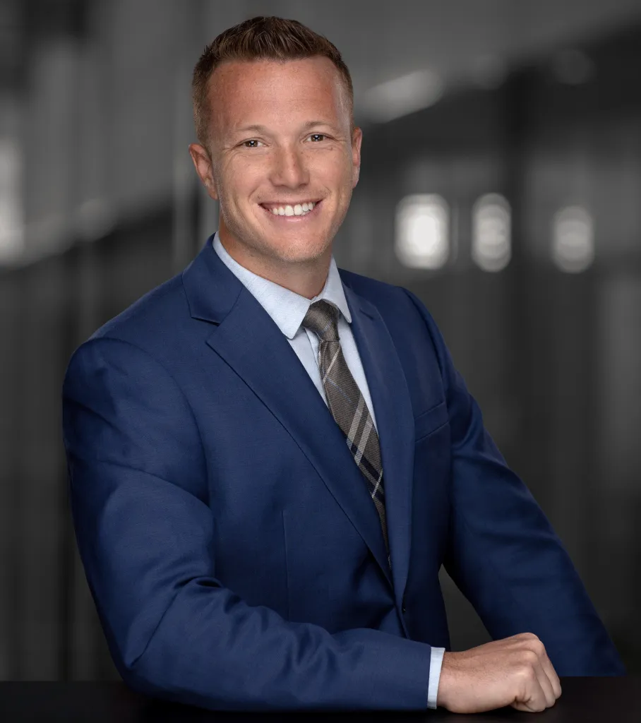 Blake Fiechter smiling, wearing a blue suit and striped tie.