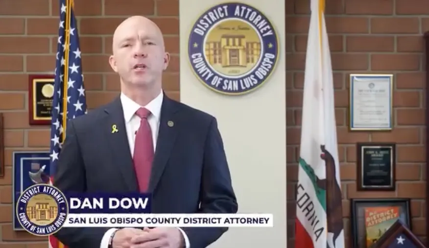 San Luis Obispo County District Attorney Dan Dow speaking in front of an American flag and the California state flag.