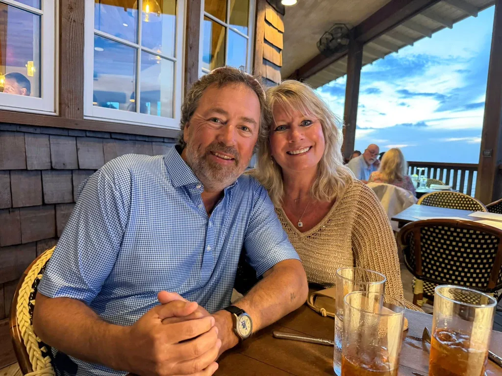 Lisa and Al Robertson smiling while seated at an outdoor restaurant.