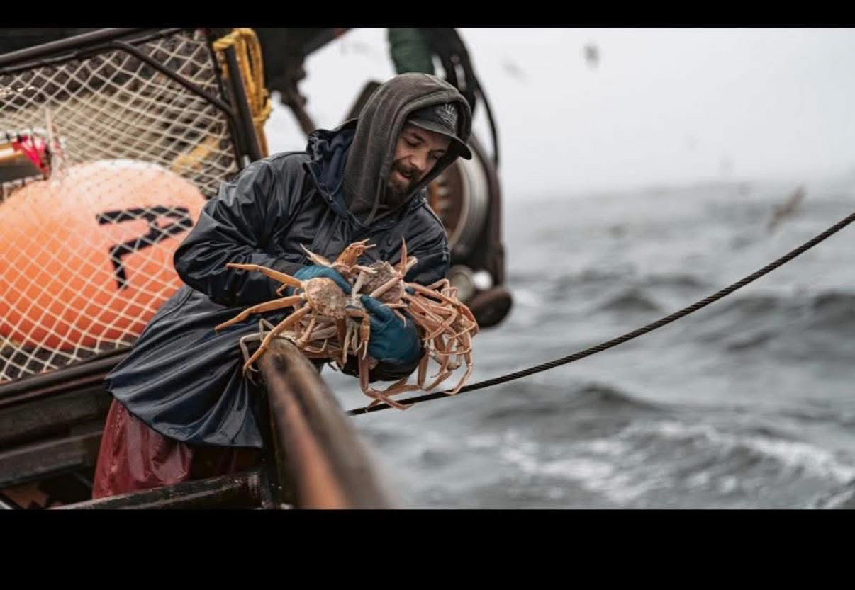 Todd Meadows, a Deadliest Catch fisherman, holding crabs on a boat.