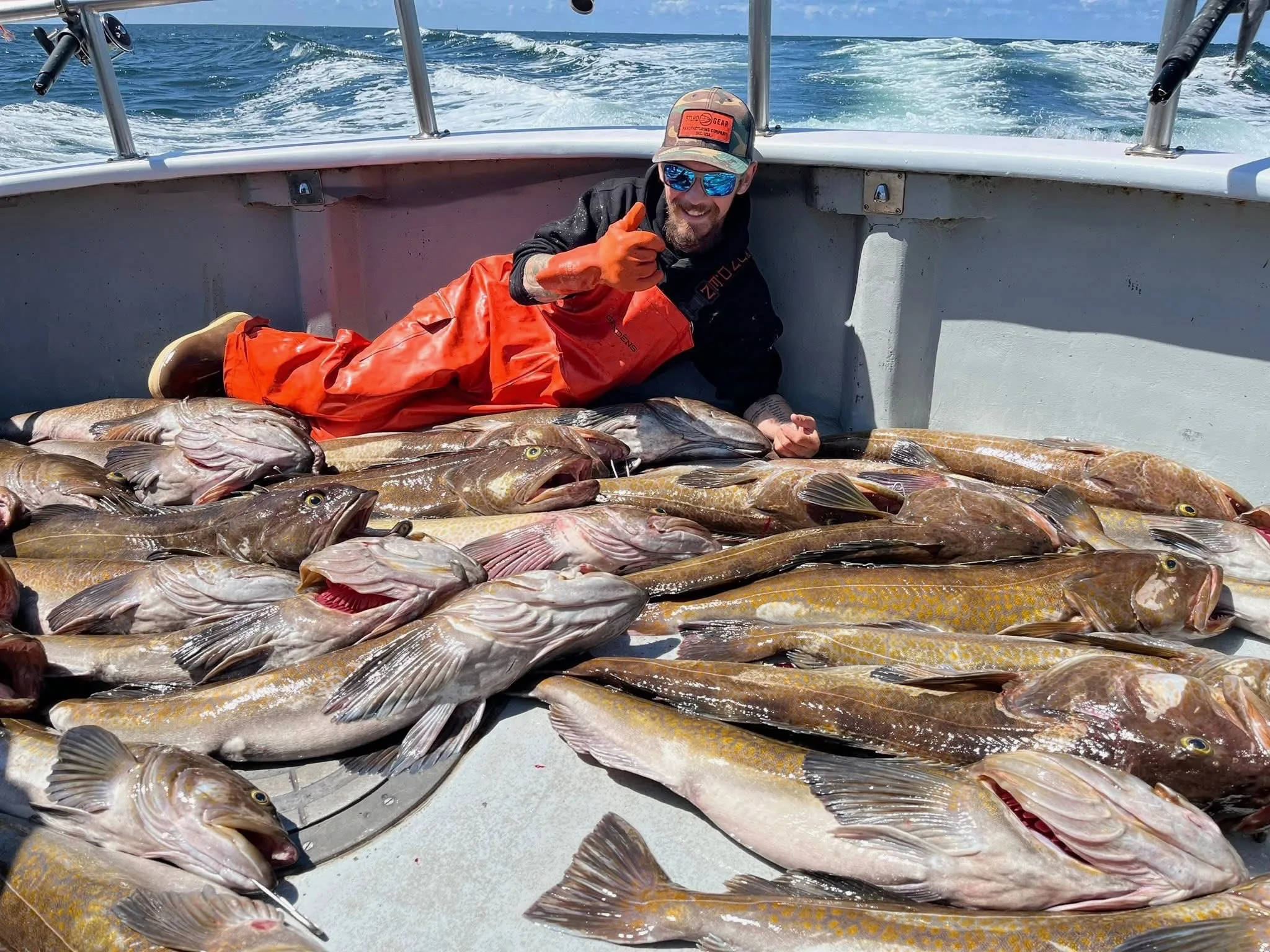 Todd Meadows on a boat, surrounded by a large catch of fish, giving a thumbs-up.