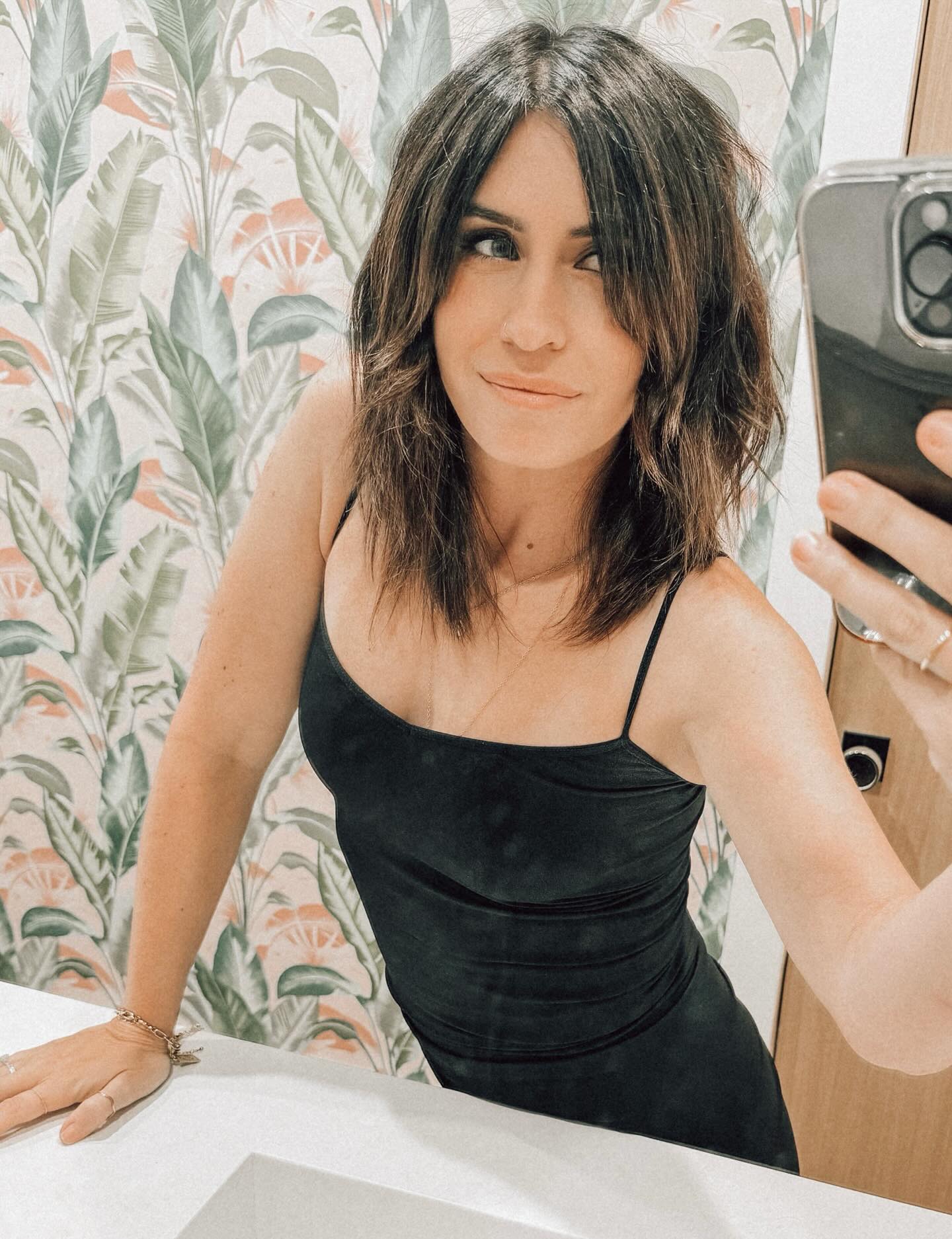 Brittney Shomo, wife of Caleb Shomo, poses for a mirror selfie in a black dress.