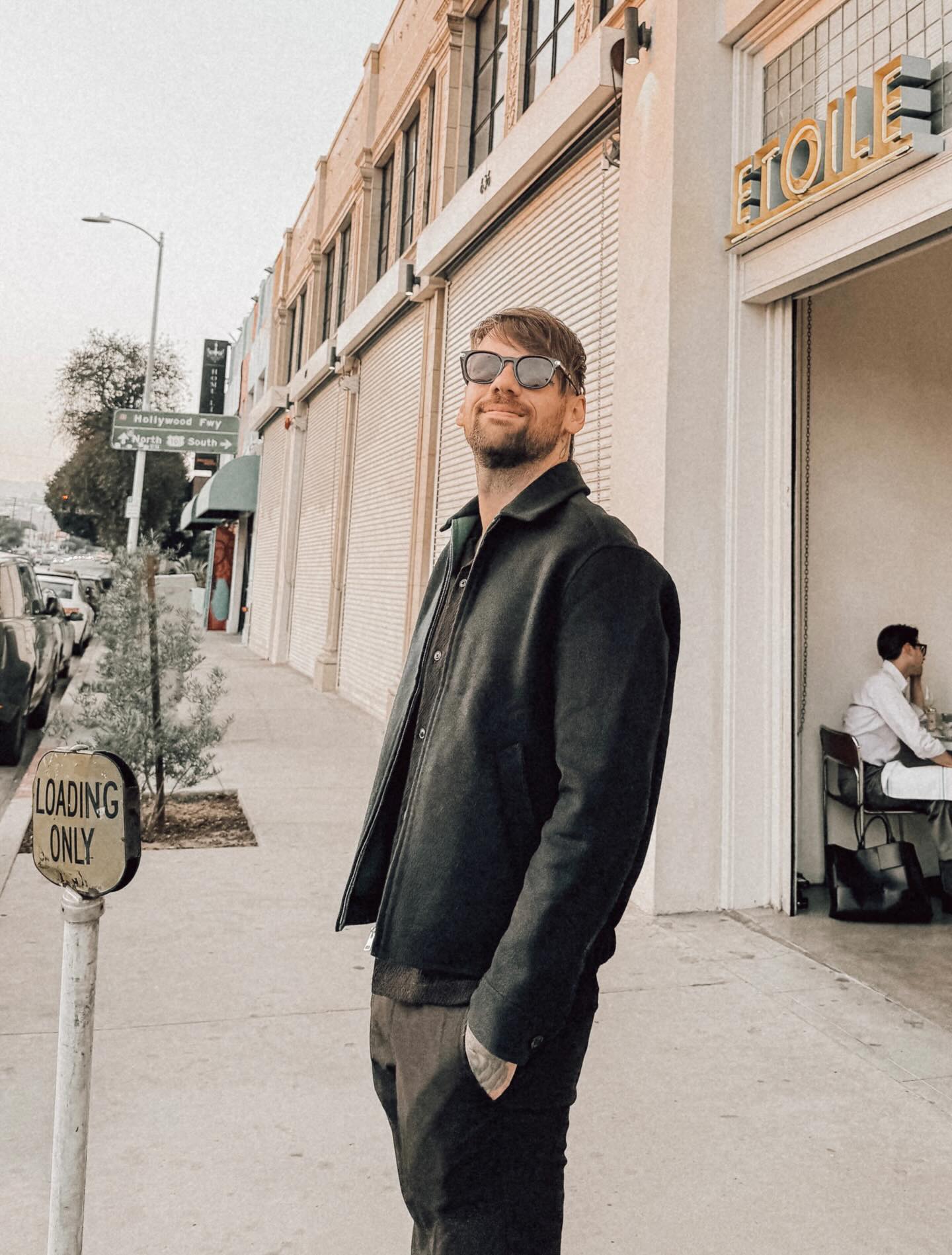 Caleb Shomo standing on a sidewalk next to a 