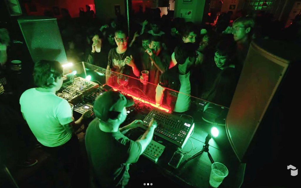 A DJ performing in Club Japan, Mexico City, with a crowd of people watching.