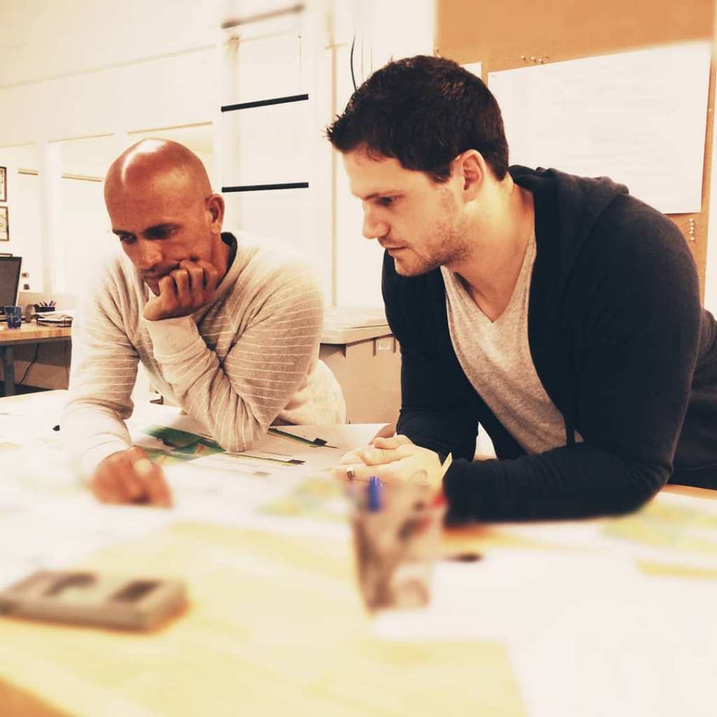 Two men, Alex Poirot (left) and another scientist (right), lean over a desk looking at documents.