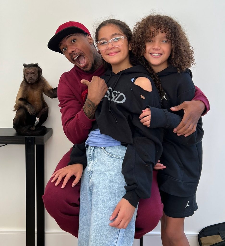 Nick Cannon with daughters Moroccan and Monroe, and a monkey on a stand.