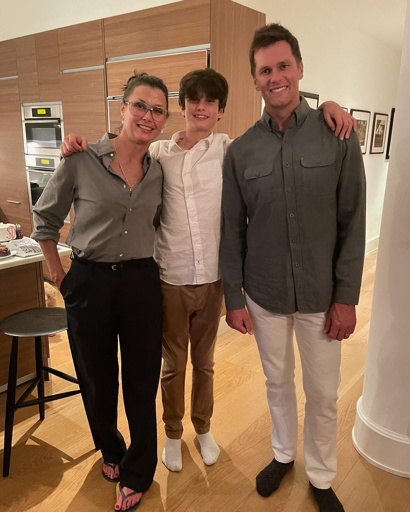 Tom Brady, Bridget Moynahan, and their son Jack standing together in a kitchen.