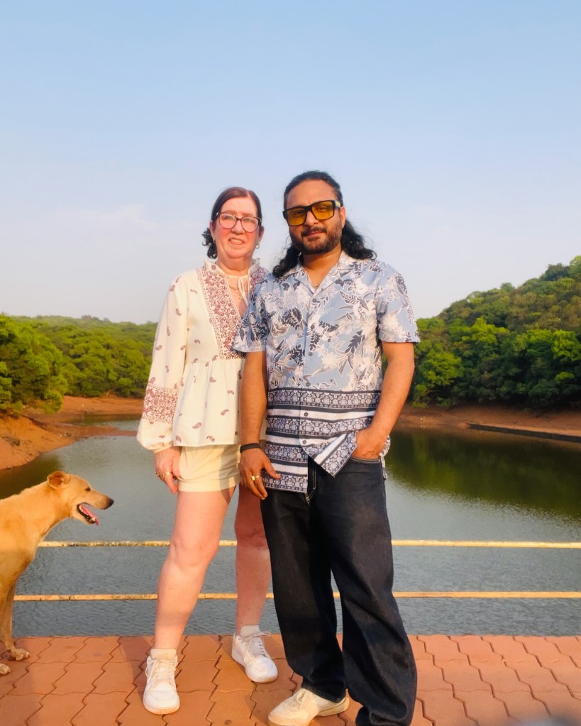 Jenny Slatten and Sumit on a bridge overlooking a body of water with a dog beside them.
