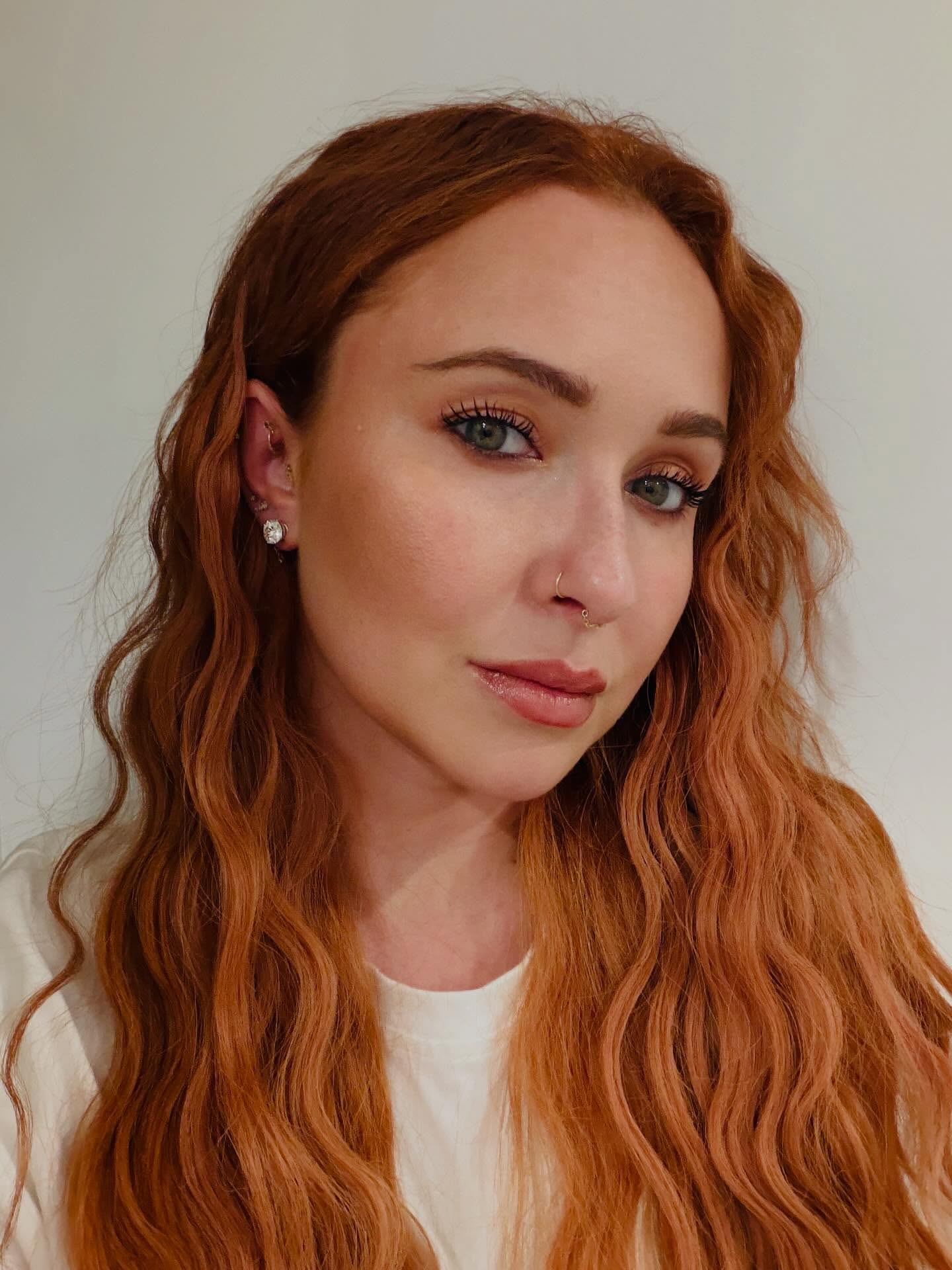 Hayden Panettiere with long wavy auburn hair, dark eyeshadow, a nose ring, and multiple ear piercings.