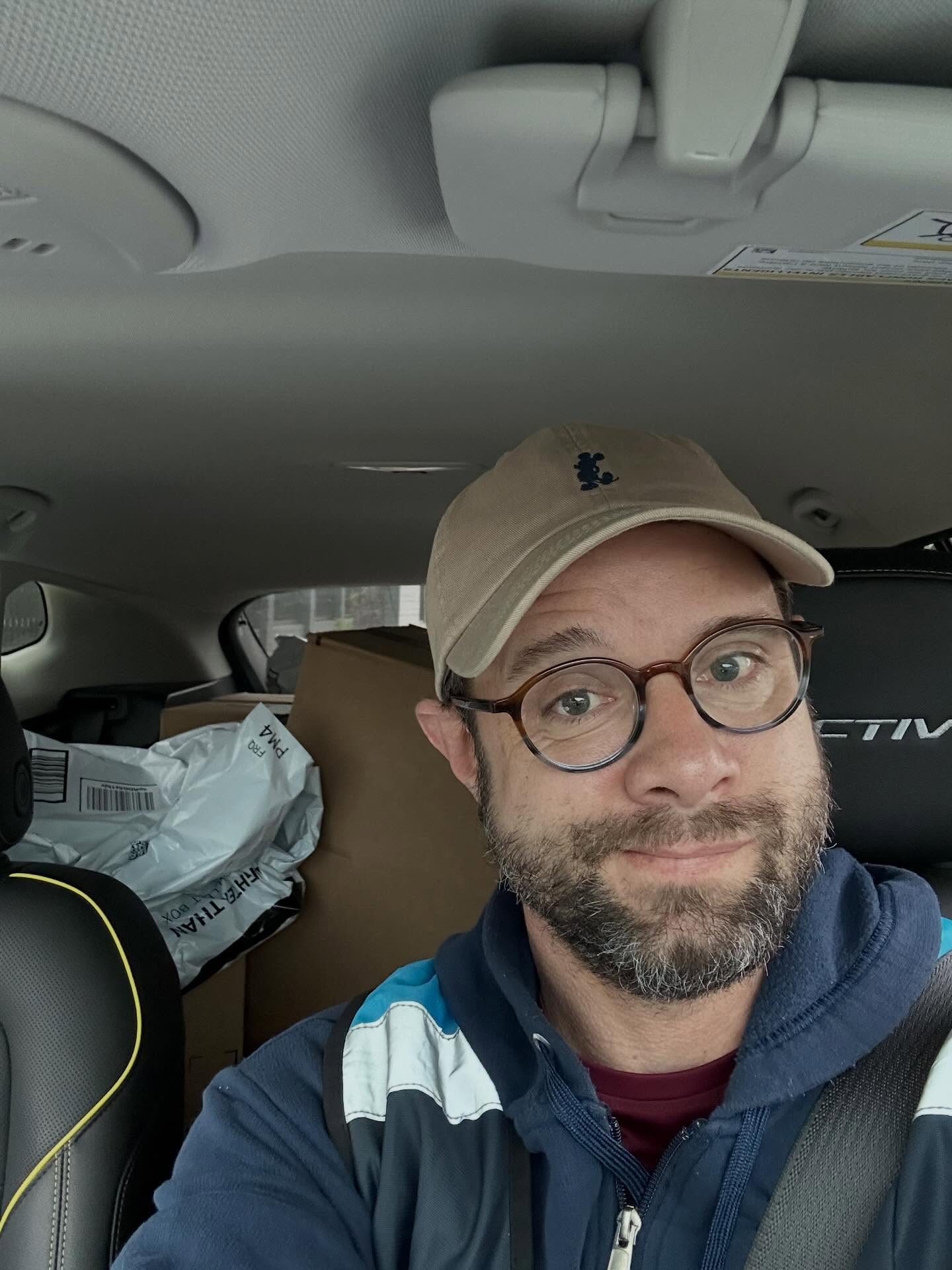Danny Pintauro, a former child actor, wearing an Amazon delivery uniform and driving a vehicle filled with packages.