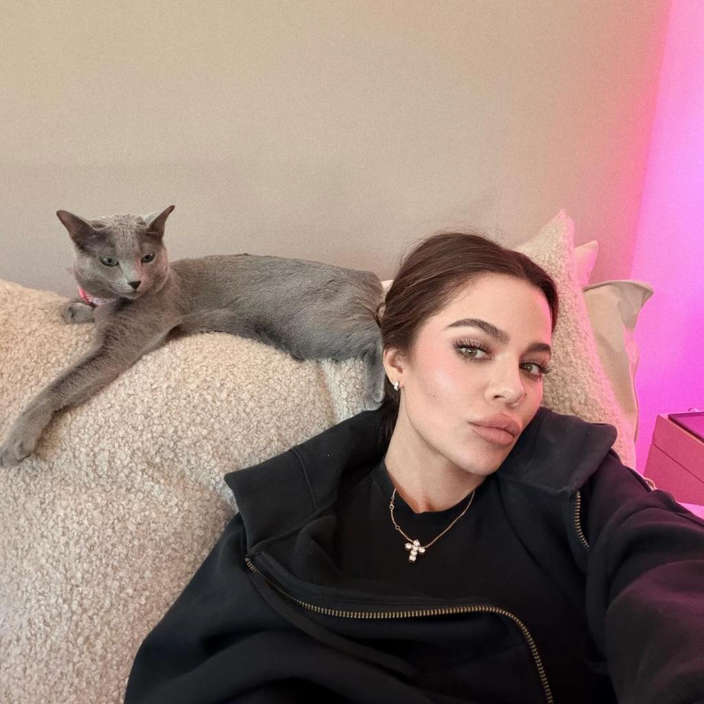 Khloe Kardashian taking a selfie with her cat on a sofa.