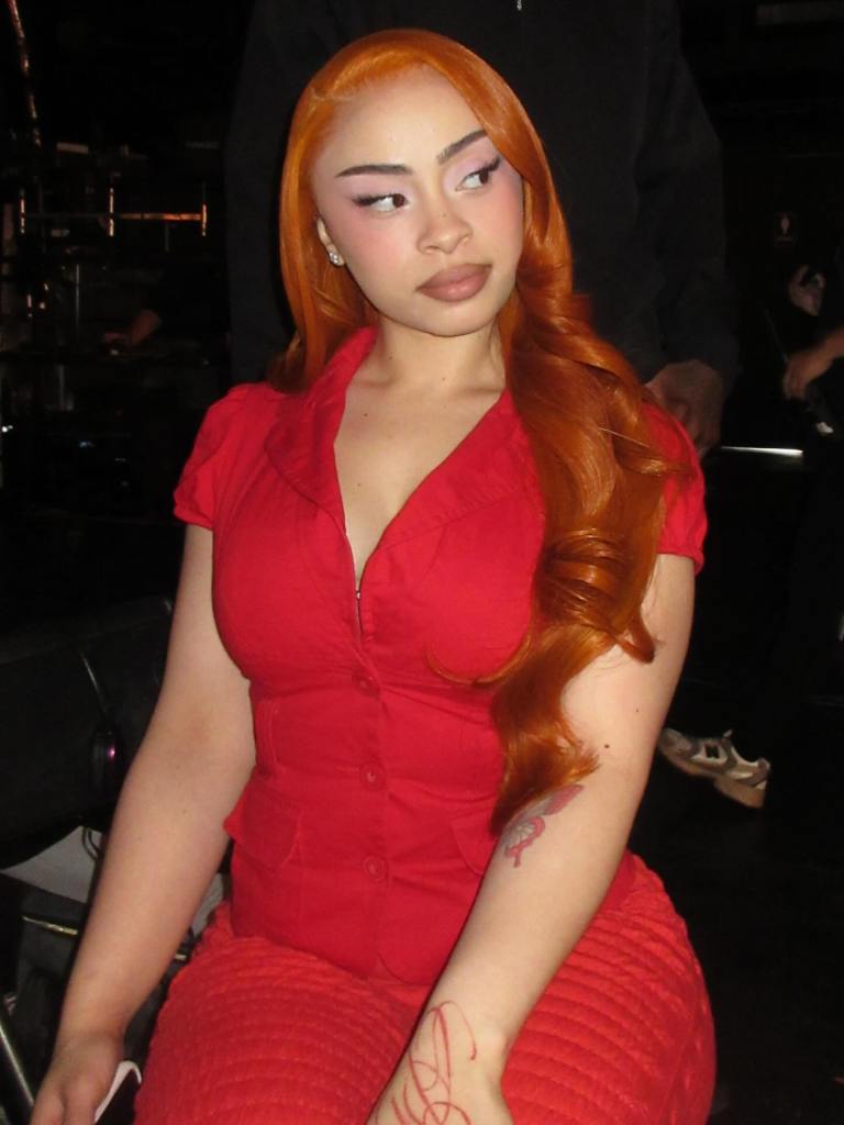 Ice Spice wearing a red top and red pants with long ginger hair.