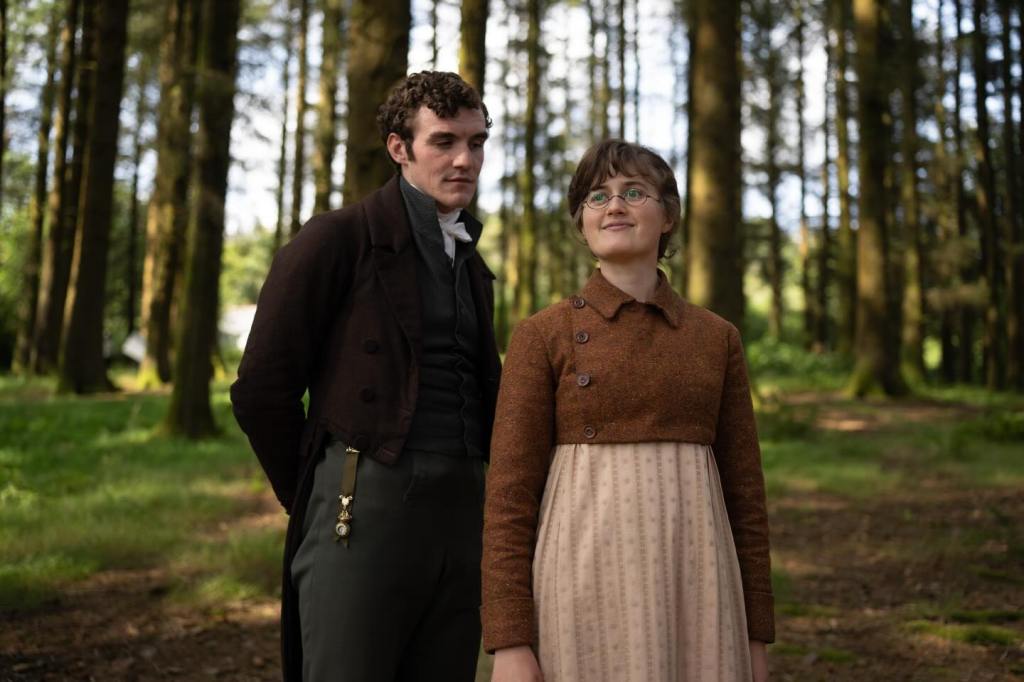 Donal Finn and another actor in period costumes standing in a forest.