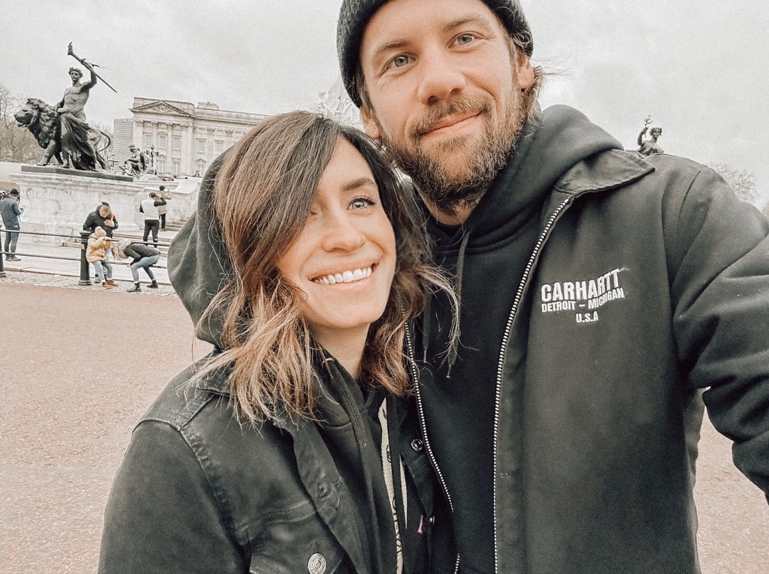 Fleur Shomo and Caleb Shomo smiling together with Buckingham Palace in the background.