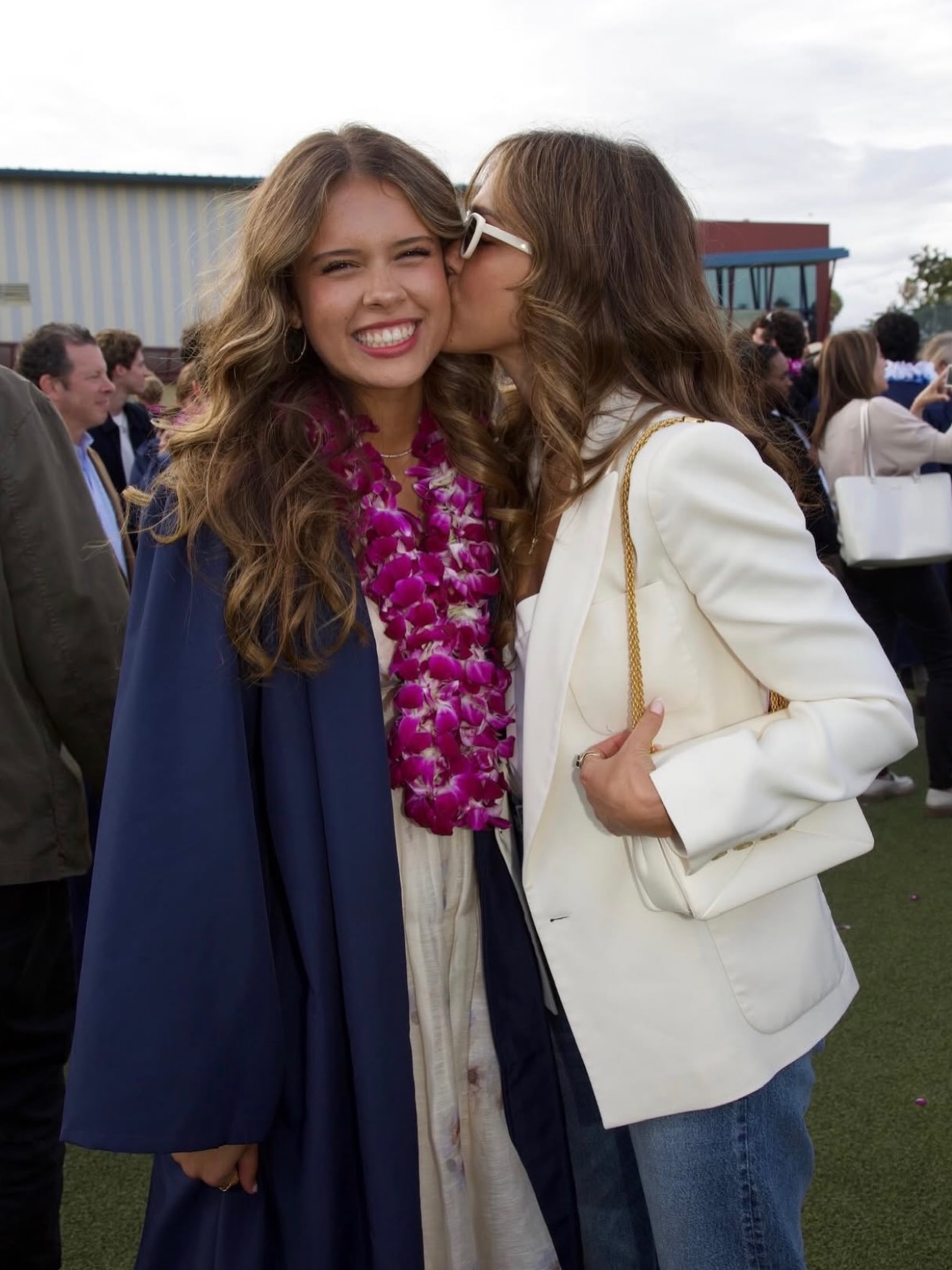 Jessica Alba kissing her daughter, Honor, who is wearing a graduation cap and gown, on the cheek.