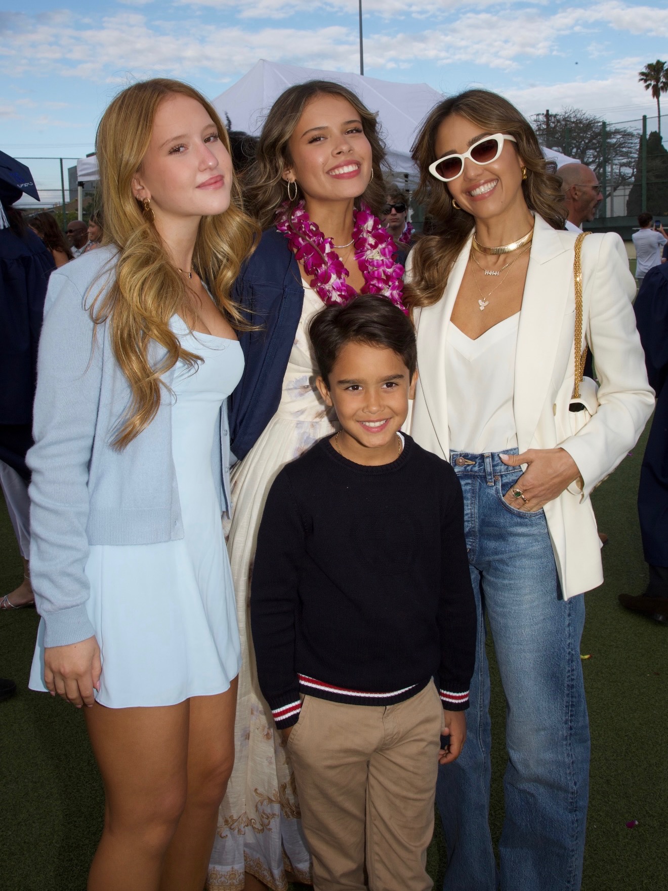 Jessica Alba posing with her three children at a graduation ceremony.