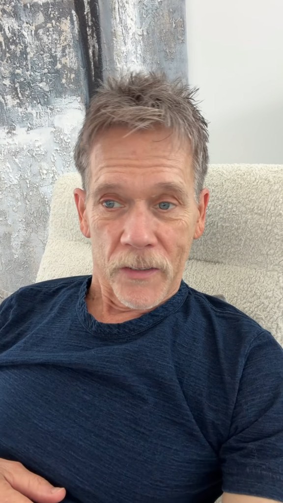 Kevin Bacon sitting in a chair, talking to the camera.