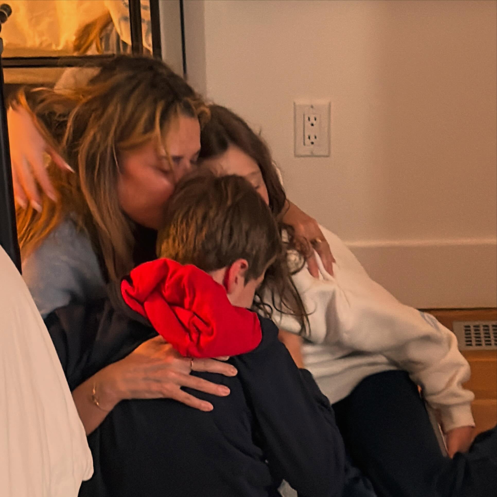 Savannah Guthrie kisses a child on the head while another child hugs them.