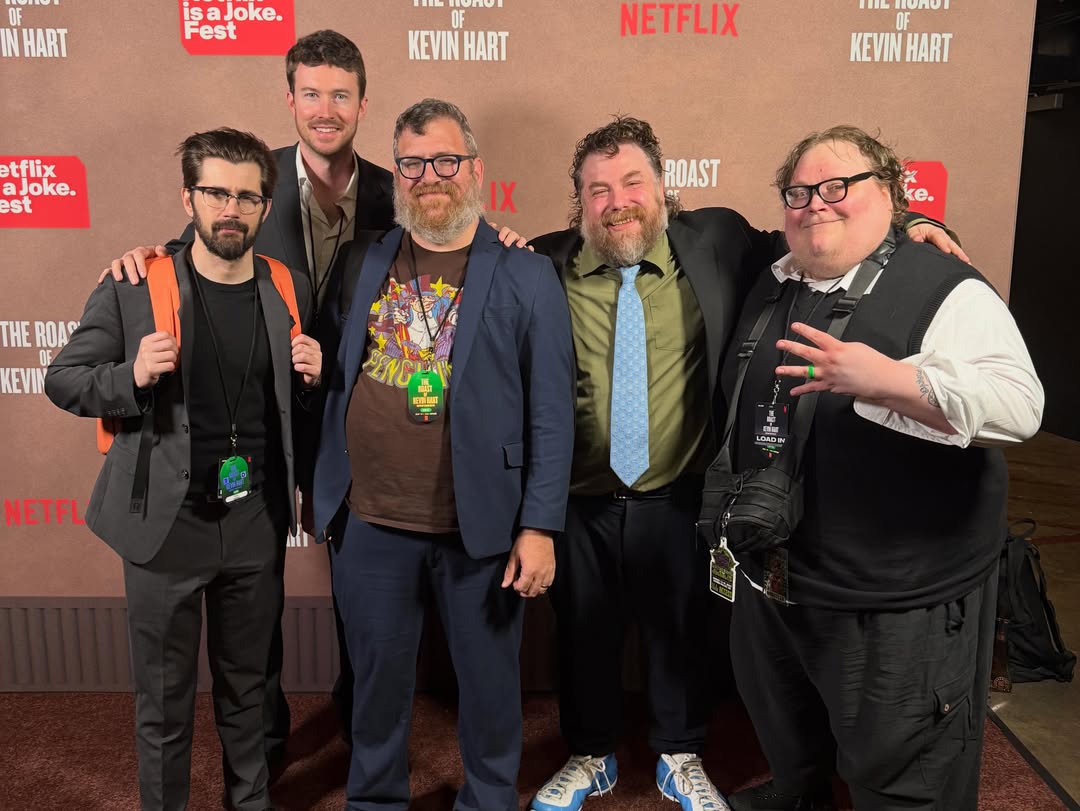 Five men pose for a photo in front of a Netflix backdrop.
