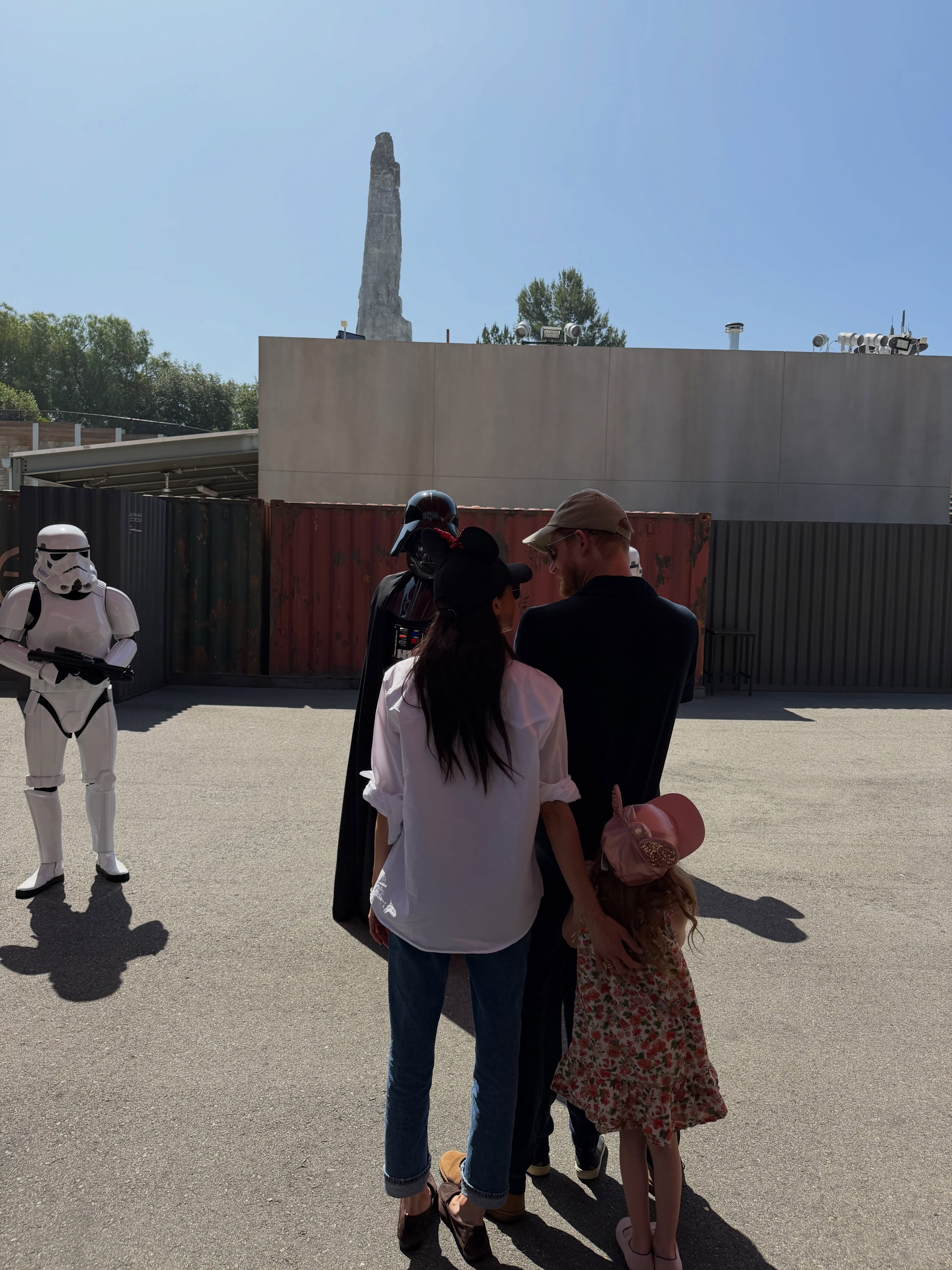 Meghan Markle, Prince Harry, and their daughter with Darth Vader at Disneyland, with a Stormtrooper nearby.