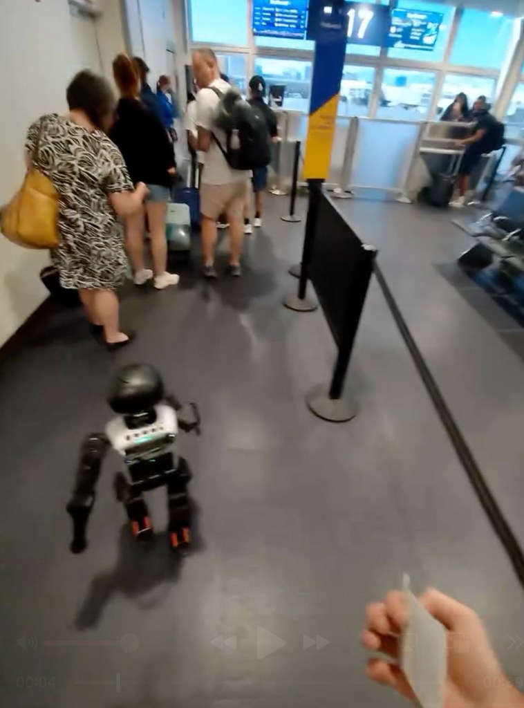 A small black and silver robot at an airline check-in gate