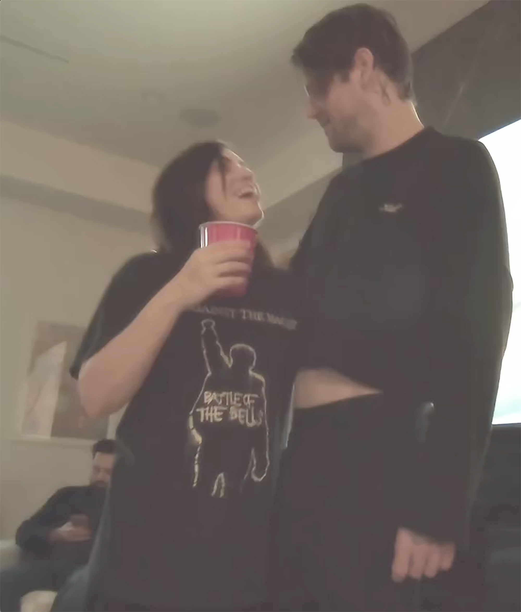 Caleb Shomo embracing his wife with a red cup in her hand.