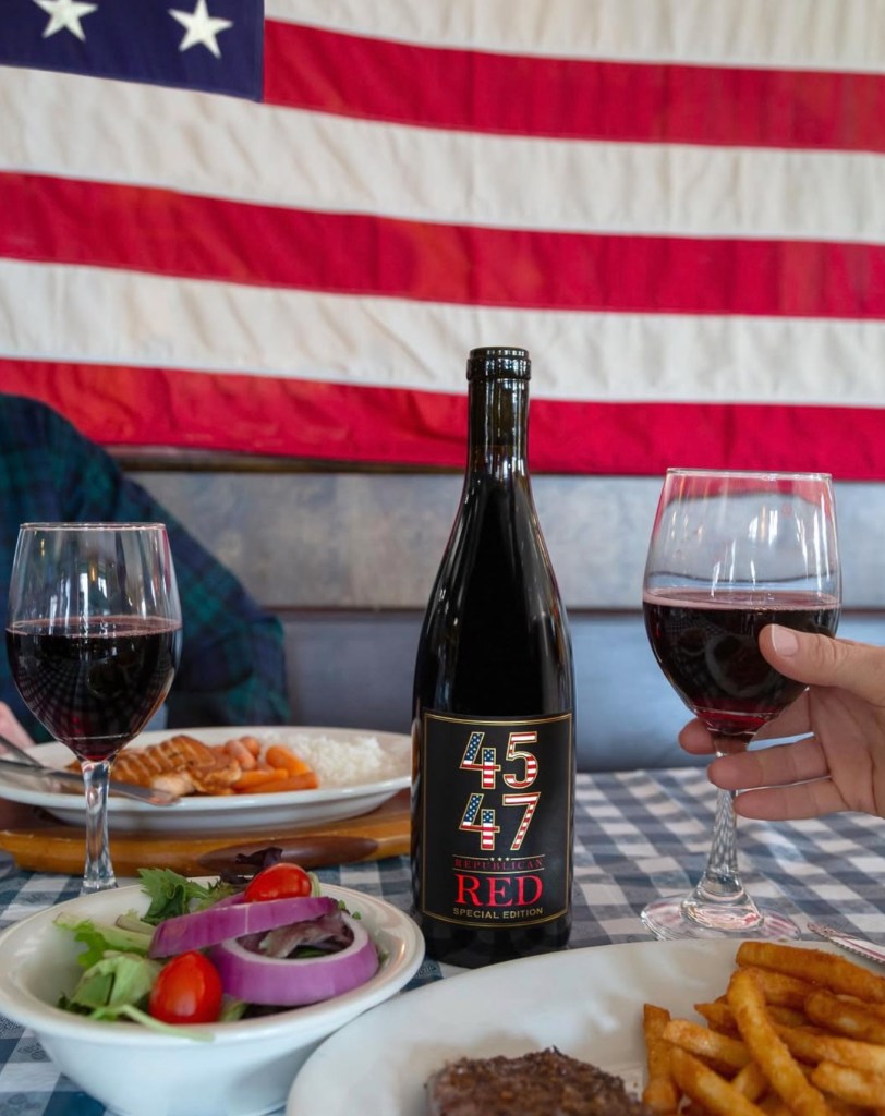 Republican Red wine bottle and glasses of wine on a table with food, with an American flag in the background.
