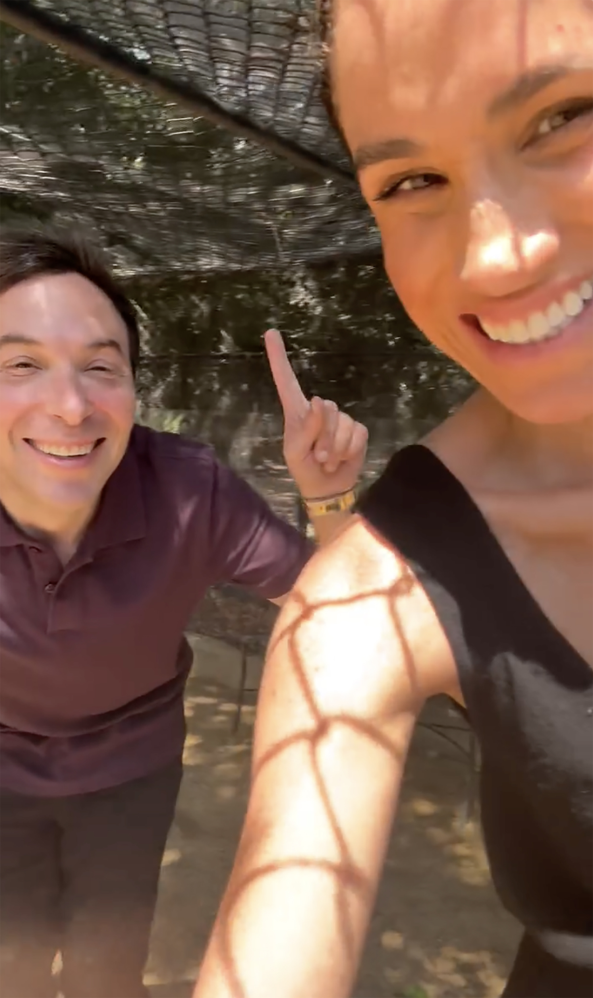 Meghan Markle and Jimmy Fallon smiling, with Fallon pointing upwards.
