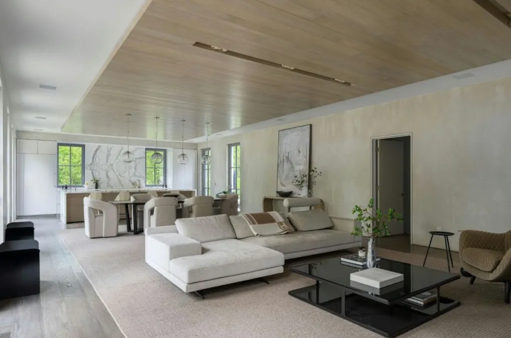 Open-concept living room with light gray sofas and an adjoining kitchen area.