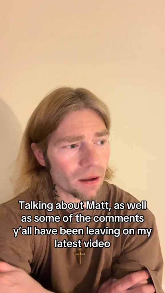 A man with blonde hair and a cross necklace speaking in a TikTok video about comments on his latest video.