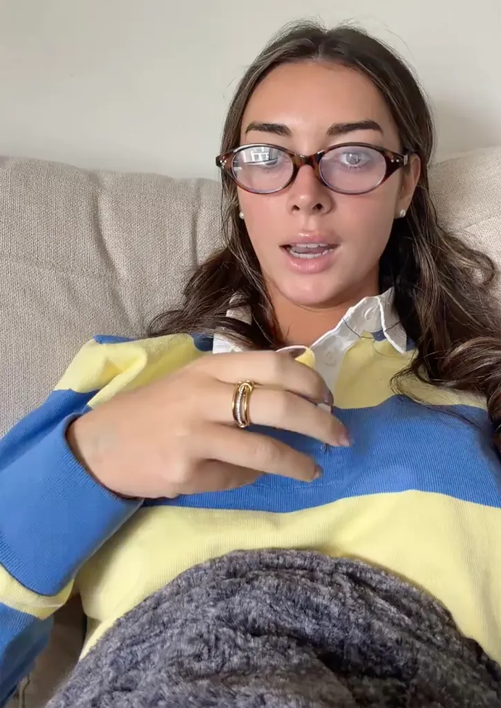A young woman with glasses and a striped shirt talks to the camera, sharing her experience after emergency surgery.