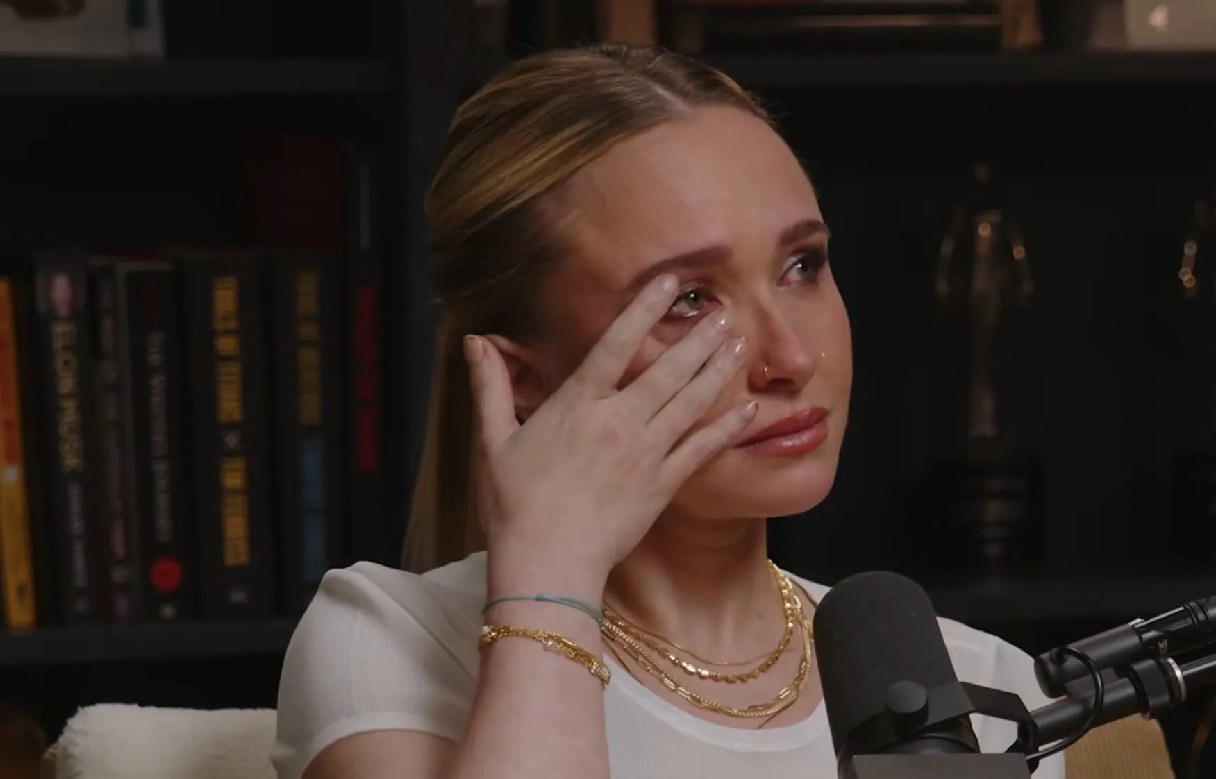 Hayden Panettiere cries on a podcast, wiping a tear from her eye.
