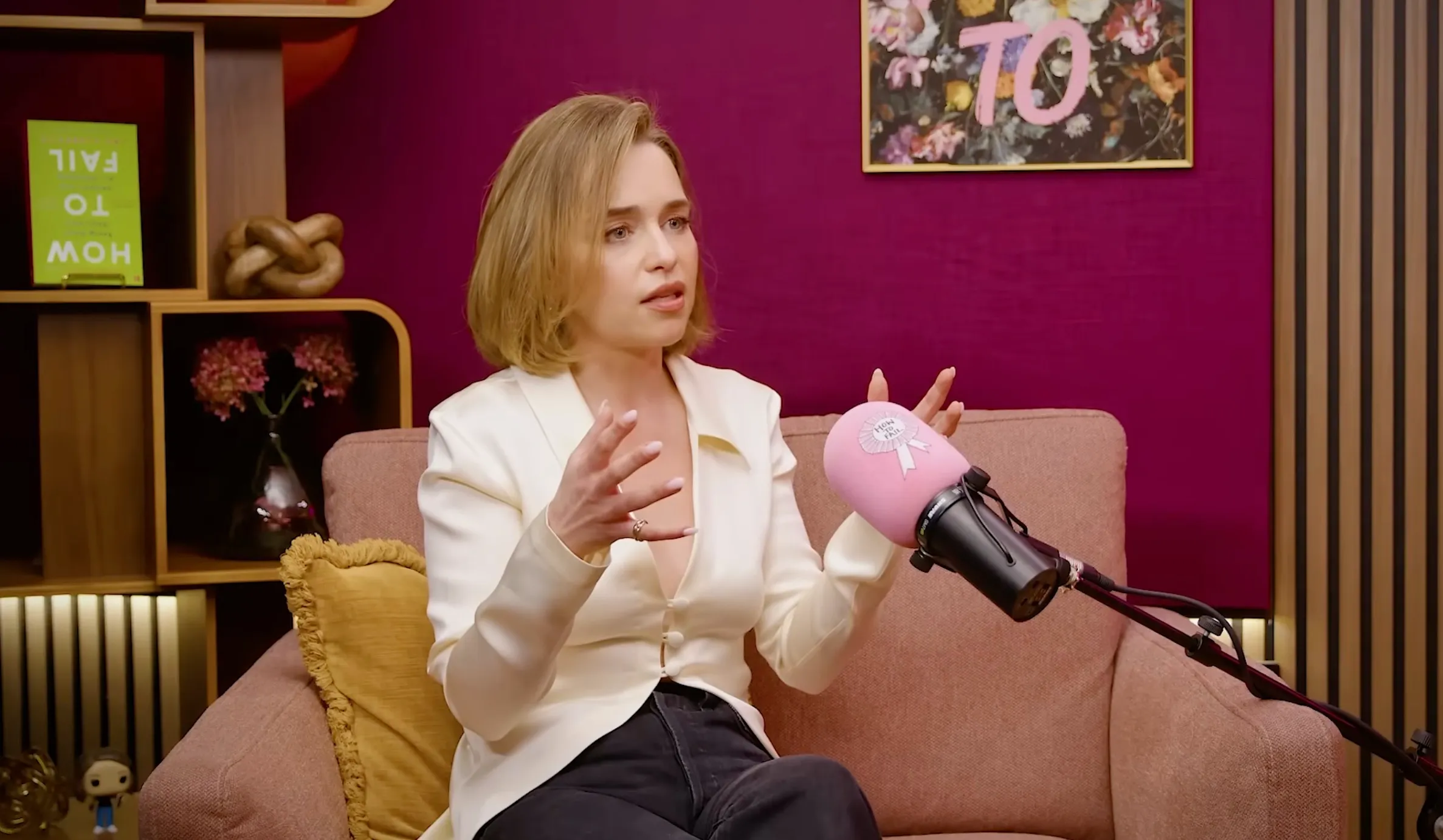 Emilia Clarke speaking into a pink microphone with 