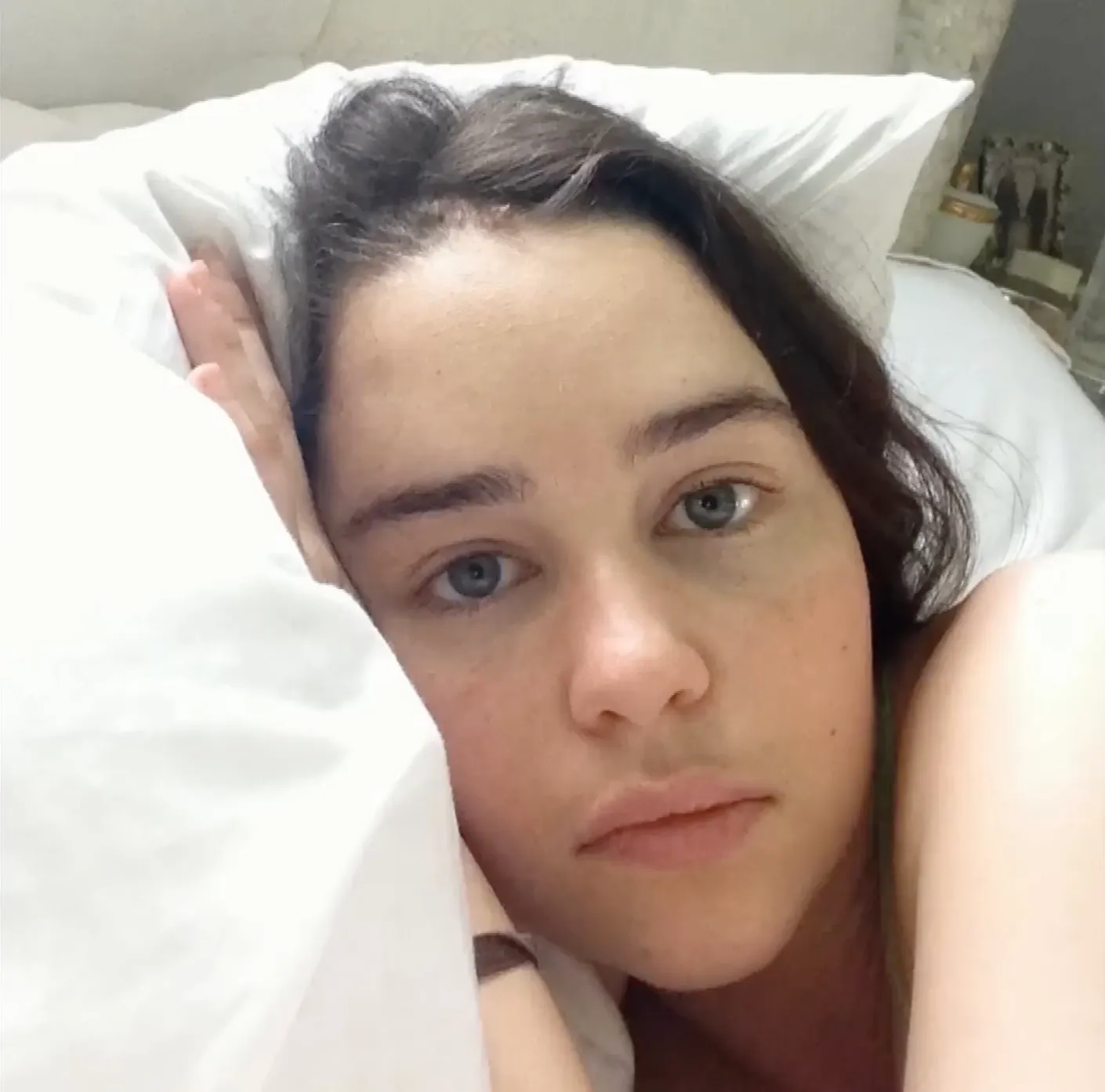 Emilia Clarke in bed, looking at the camera.