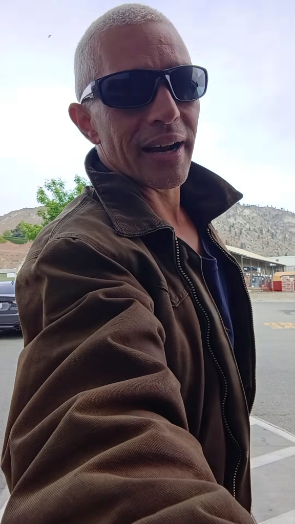 A man wearing sunglasses and a brown jacket.