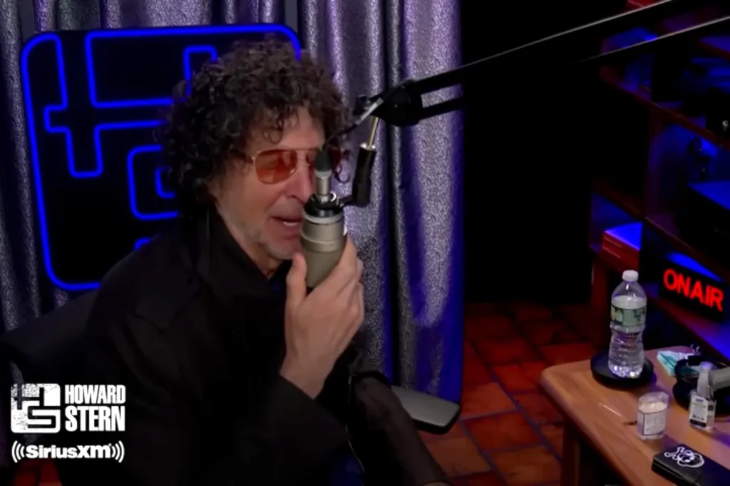 Howard Stern broadcasting from his studio, holding a microphone.