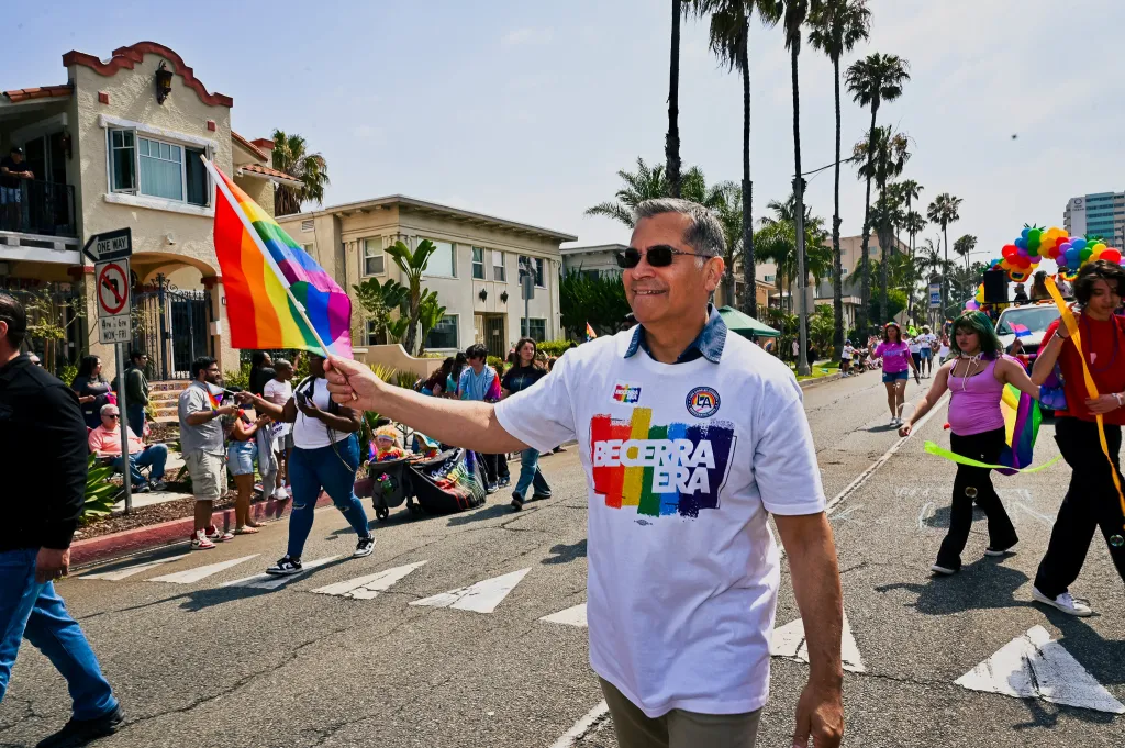 Xavier Becerra holding a rainbow flag at the Long Beach Pride Parade.