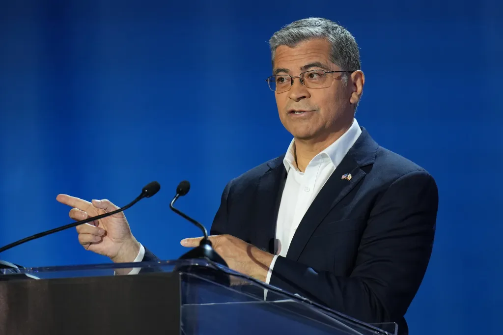 Xavier Becerra speaking at a gubernatorial debate, pointing his left hand to the side.