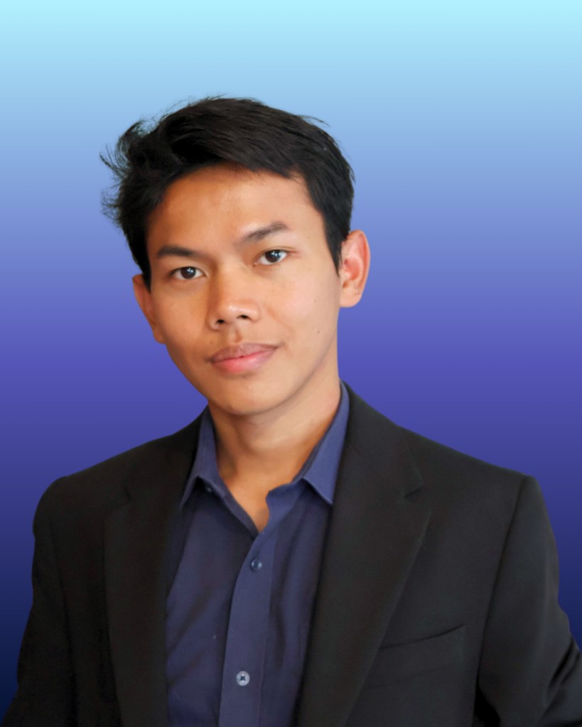 Portrait of a man in a black suit and blue shirt.
